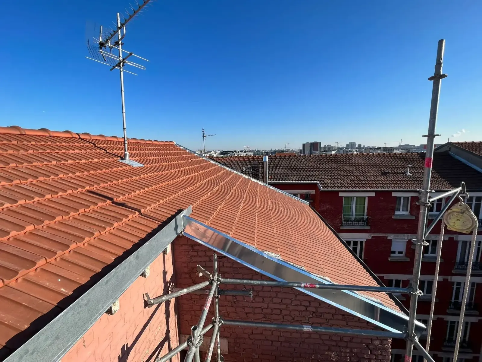 Rive en zinc posée sur une toiture en tuiles, échafaudage en place